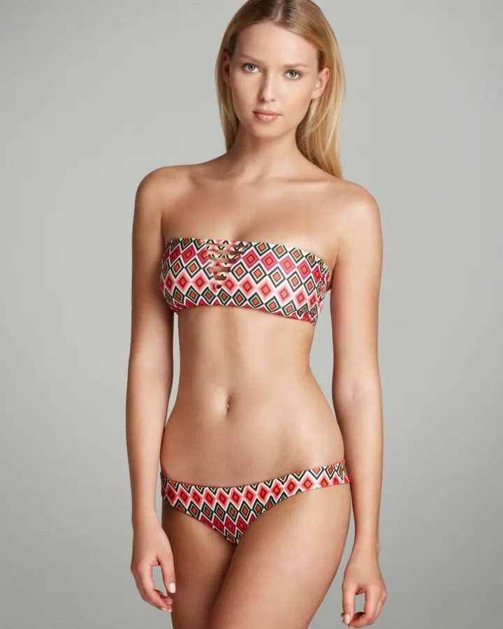 Femme blonde en bikini coloré, debout, regardant l'appareil photo